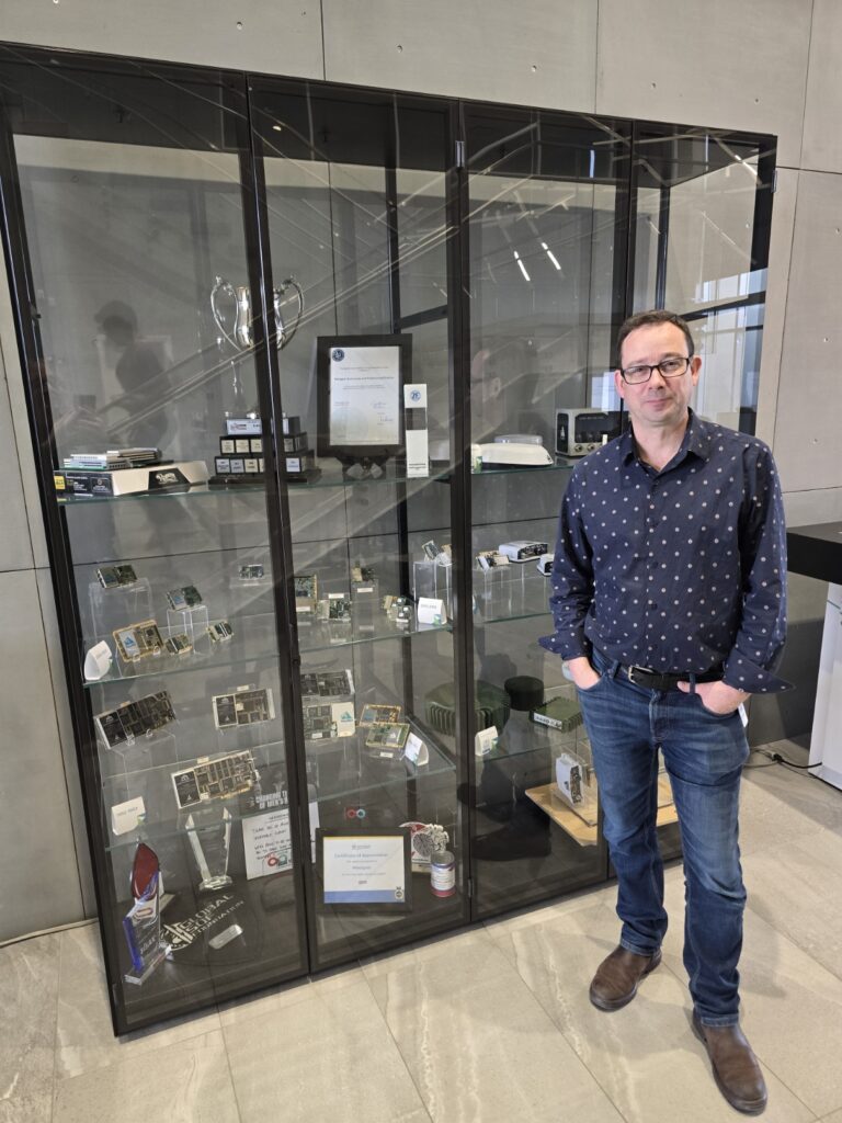 Neil Gerein, VP of Product, Aerospace & Defence Division Hexagon at the product display case in the lobby (Credit: Gavin Schrock)